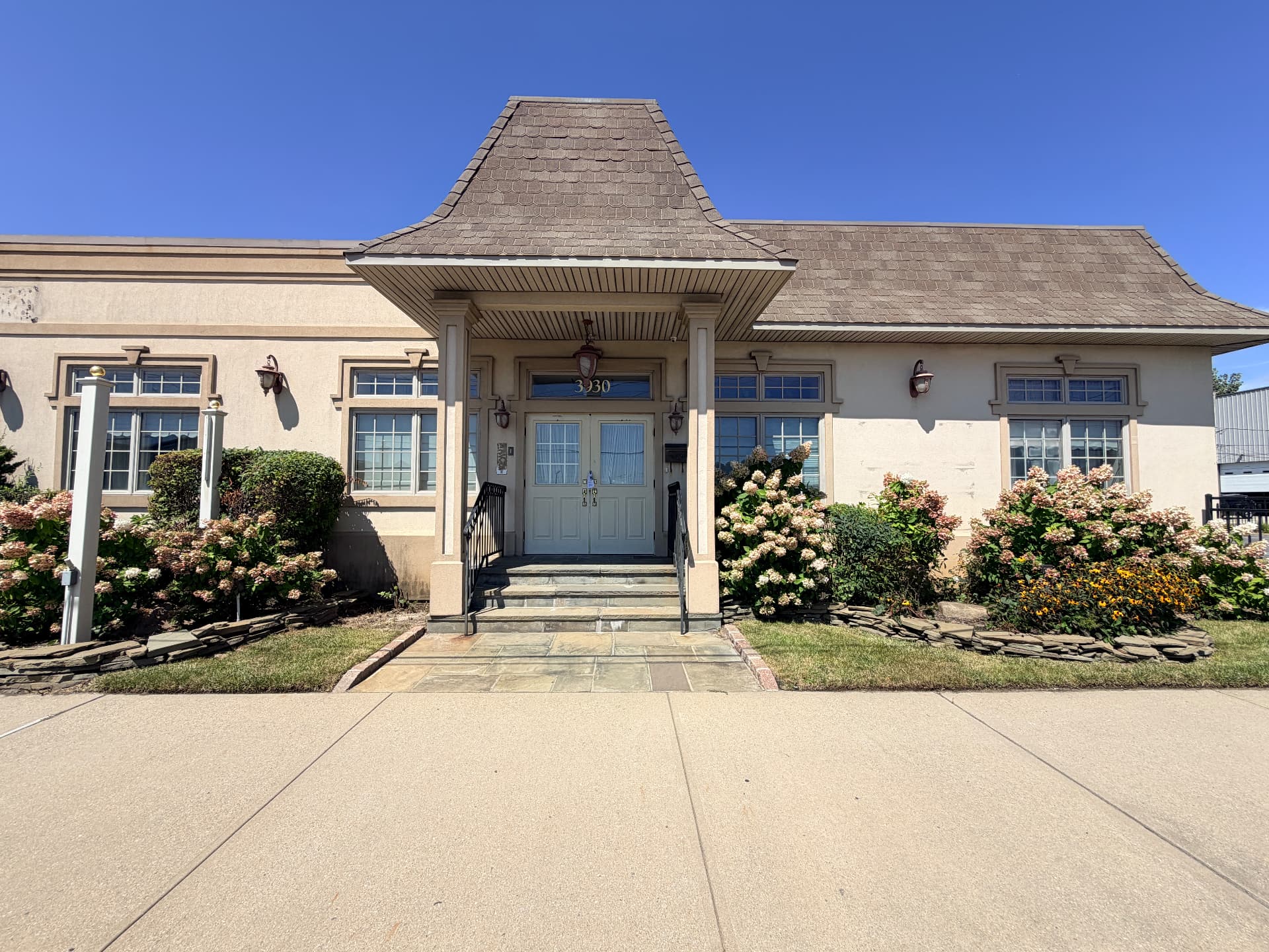 Front entrance of 3930 Long Beach Road, Island Park NY — single-story stucco building with shingled porte-cochère over the doorway